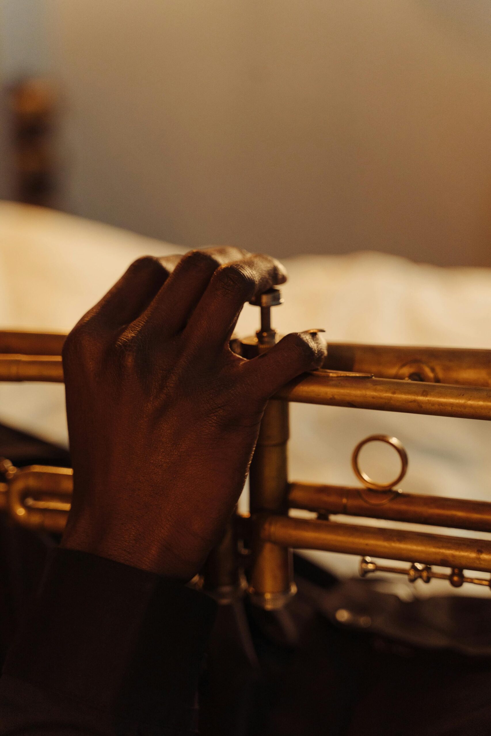 Close-up of a musician's hand playing the trumpet indoors with selective focus.