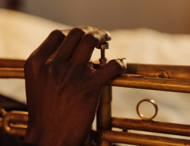 Close-up of a musician's hand playing the trumpet indoors with selective focus.
